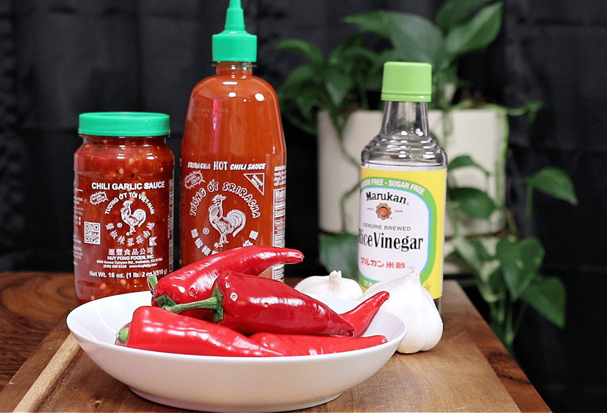 bottles of Huy Fong chili garlic sauce and sriracha along with a bowl of Red Fresno Chiles