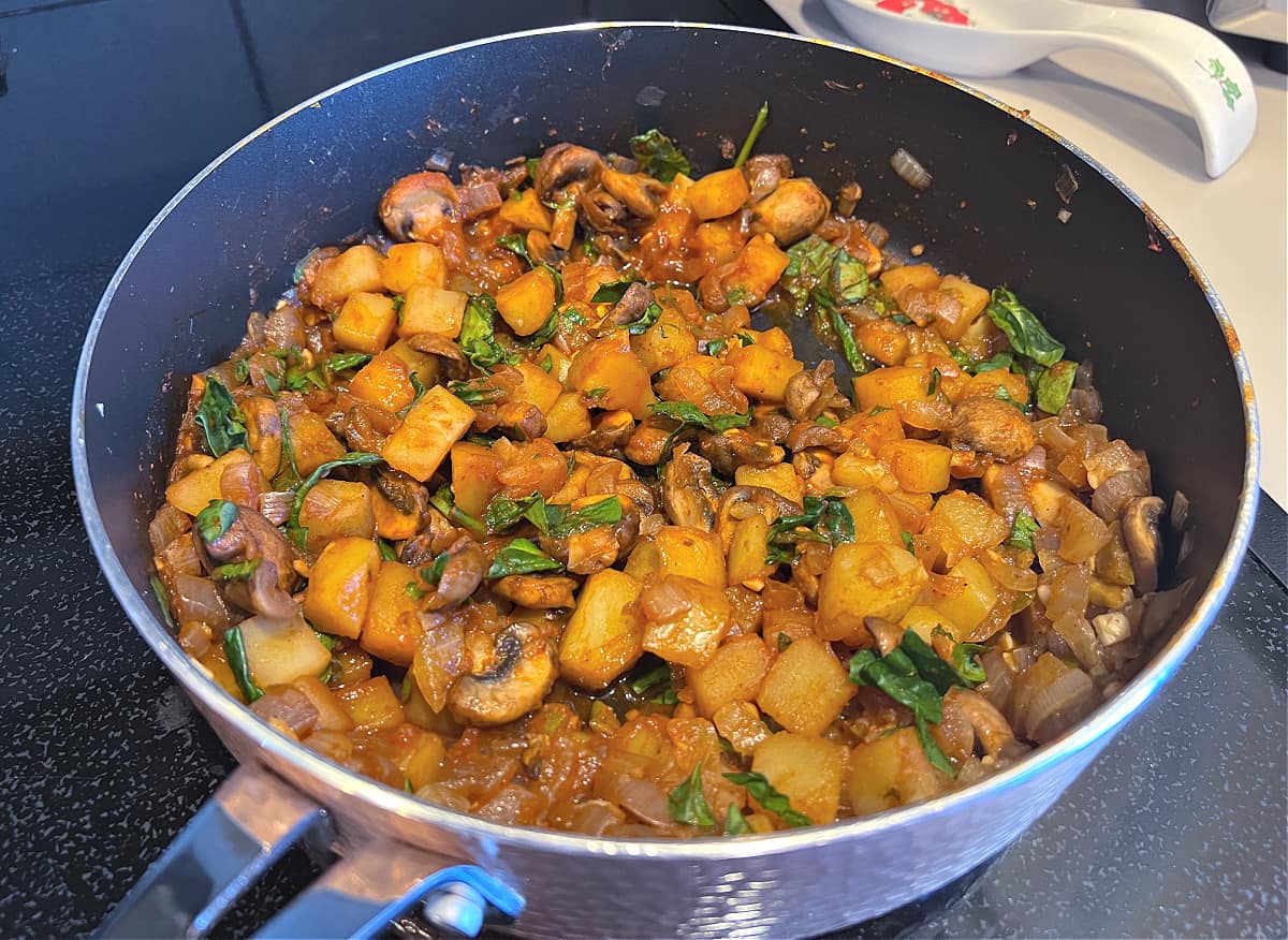 skillet of potatoes, mushrooms, onions, and spinach