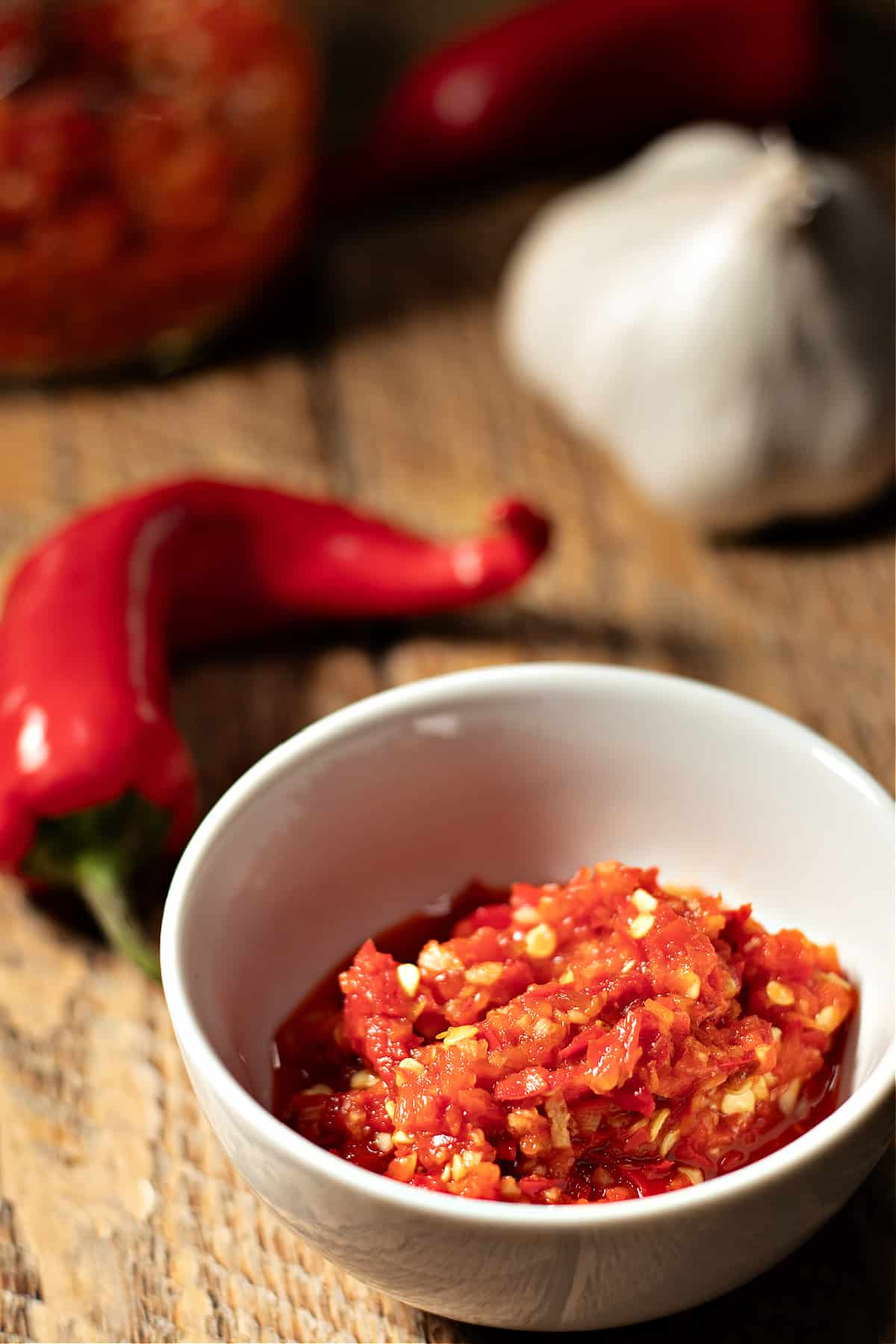 copycat chili garlic sauce displayed with a head of garlic and Red Fresno chili pepper