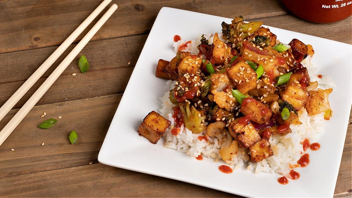 a plate of my garlic panko tofu with some chopsticks and sriracha