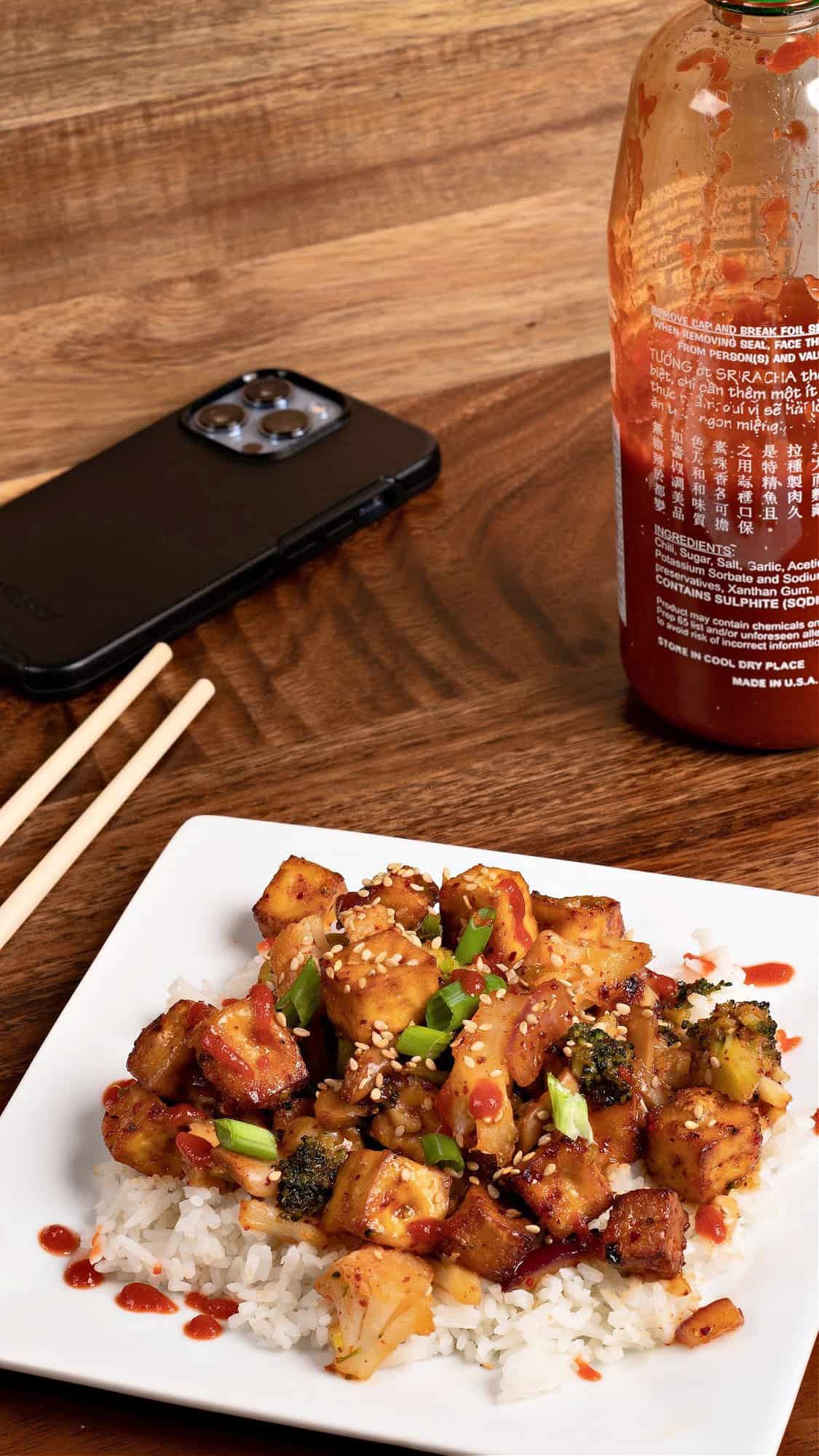 setting of my garlic panko tofu, some chopsticks, a bottle of sriracha, and my iPhone
