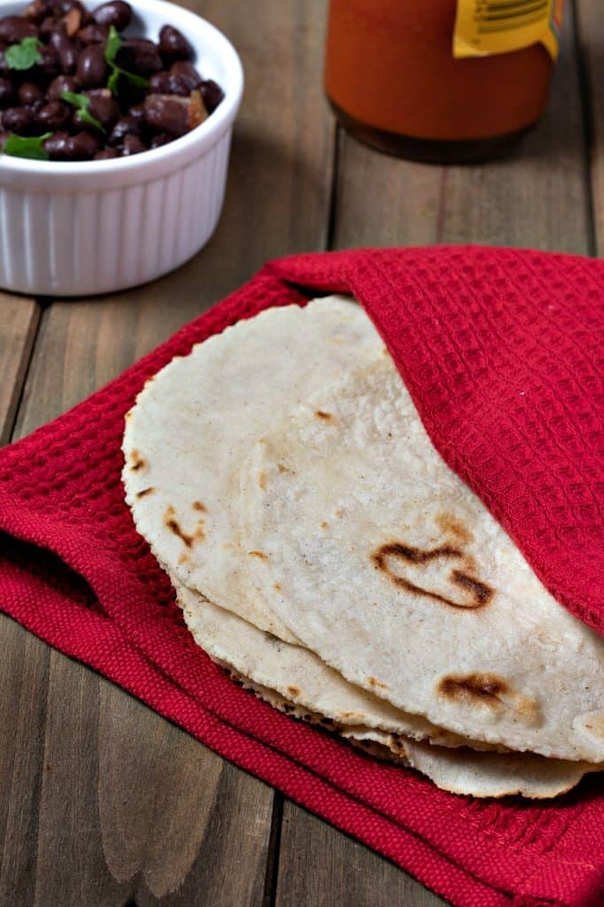 Woman makes corn tortillas by hand and cooks them on a large clay