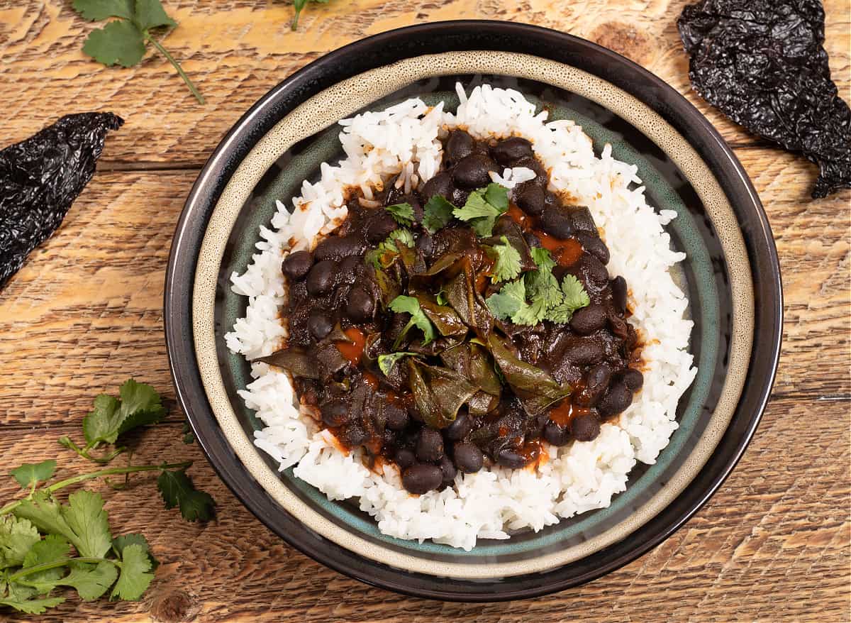 top down photo of a bowl of rice covered in Mexican beans and greens