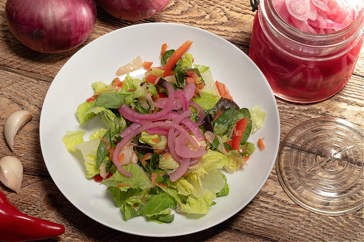 a salad with pickled onions on top