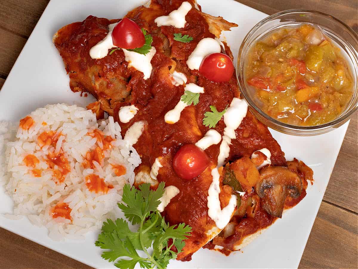 a plate of vegan potato enchiladas, rice, and green Chile sauce