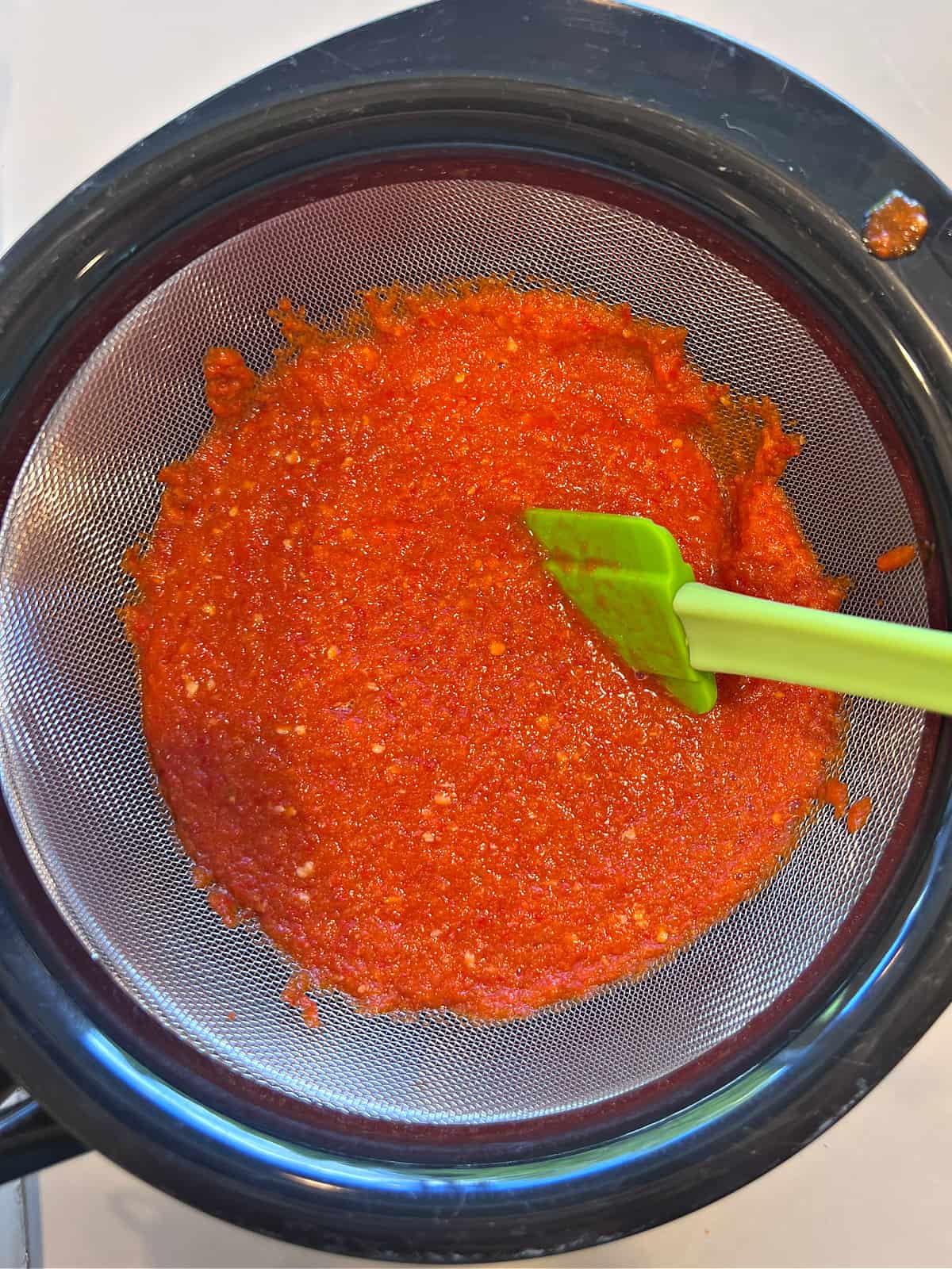 homemade sriracha being strained