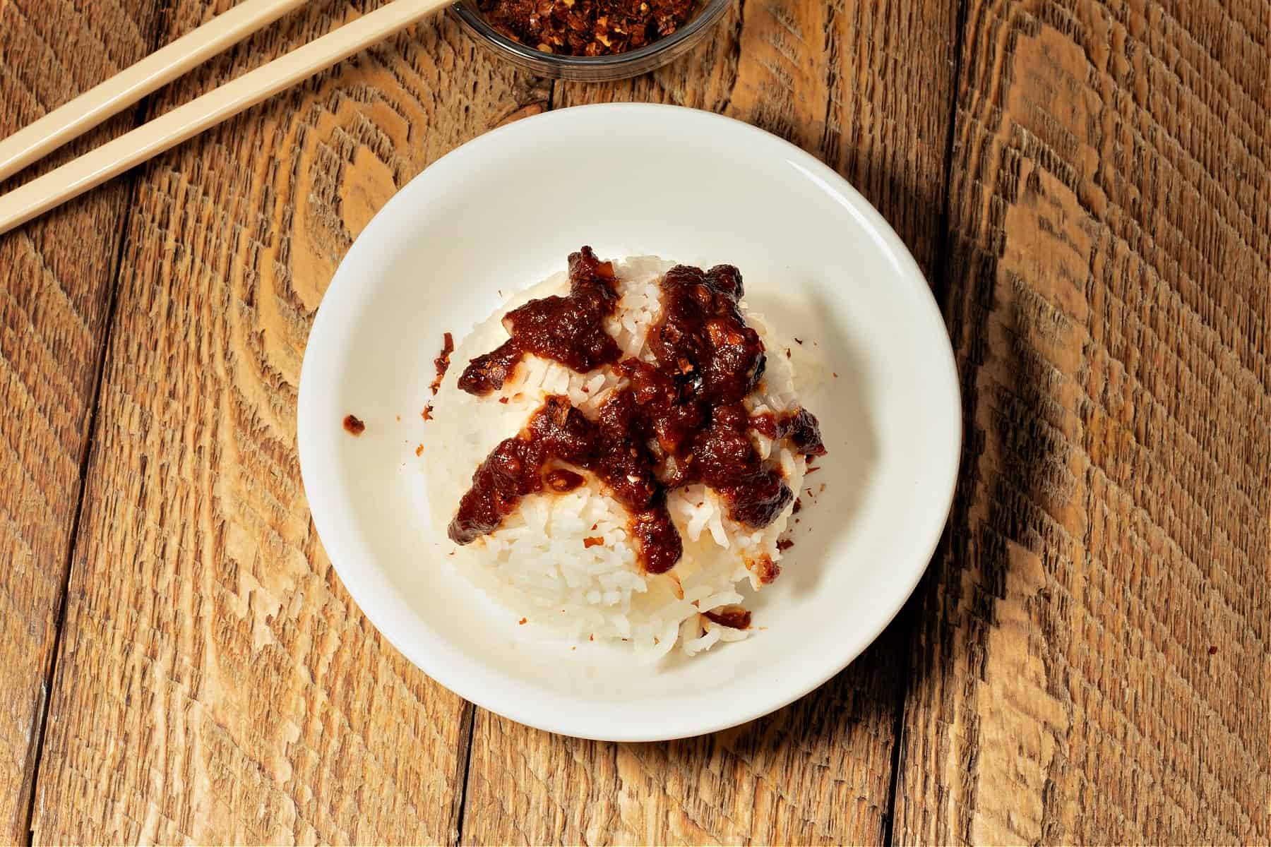 bowl of rice with chopsticks drizzled with sweet chile sauce