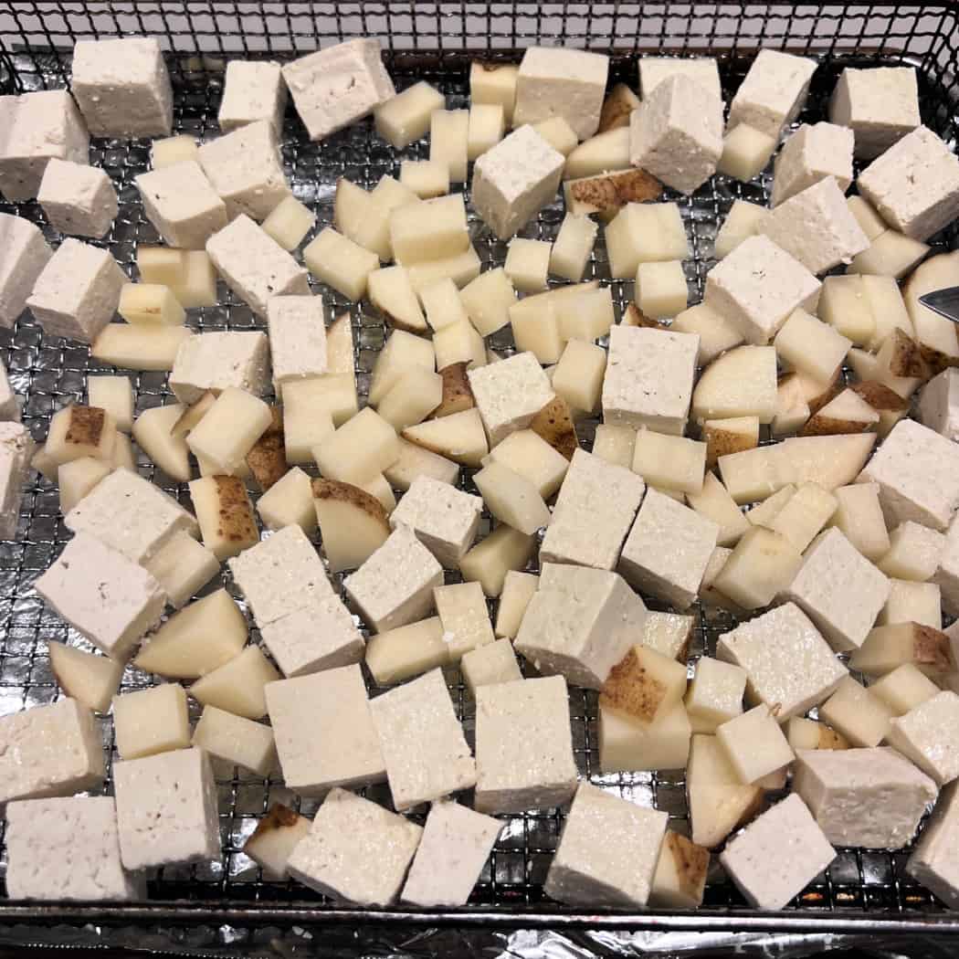 cubes of tofu and potatoes in an air-fryer basket