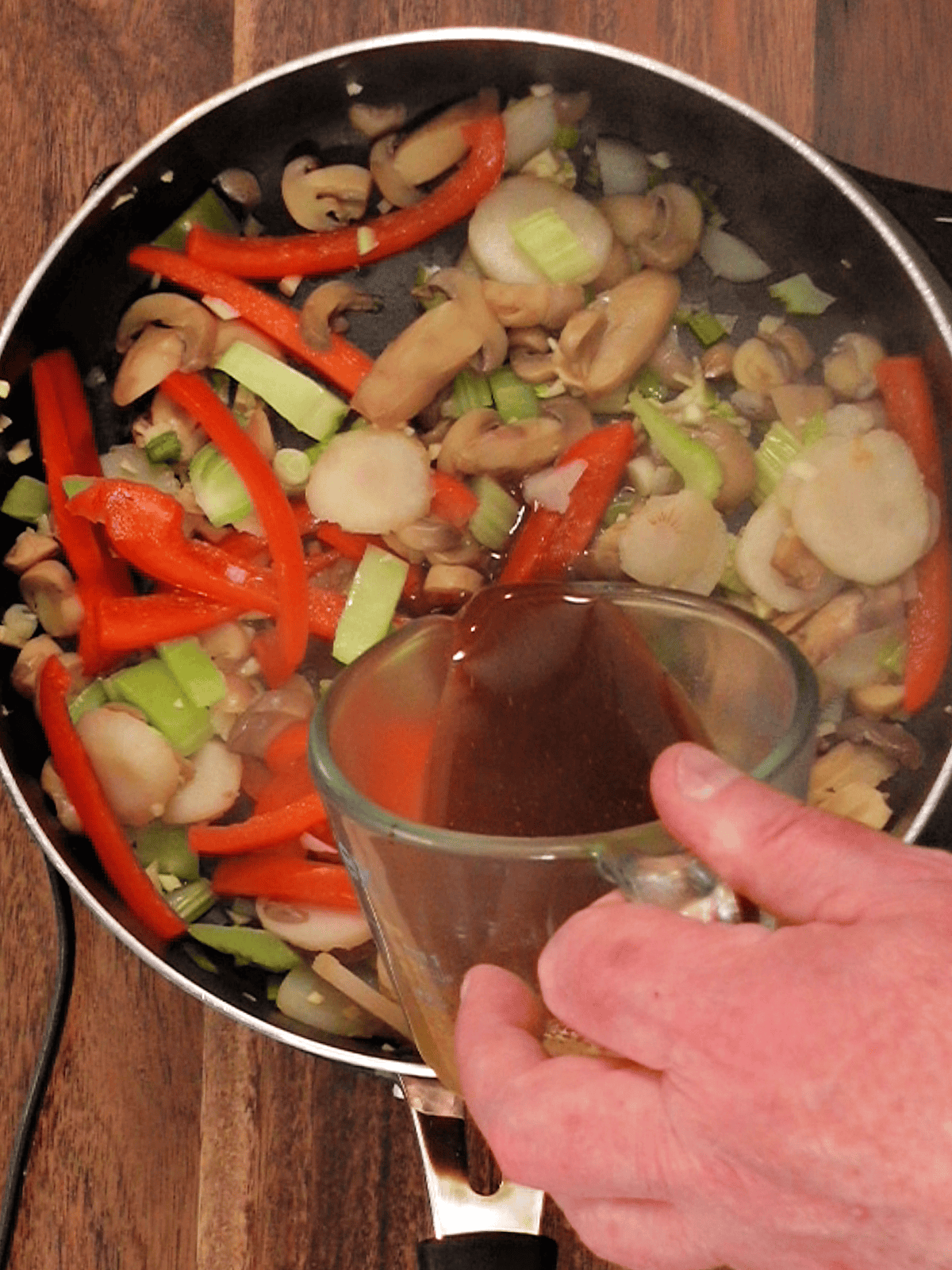 adding the sauce to vegan cashew chicken stir fry
