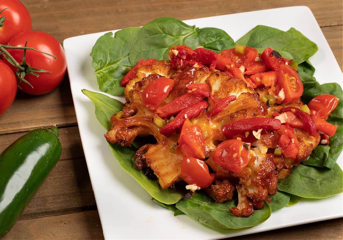 vegan cauliflower steaks on a bed of spinach