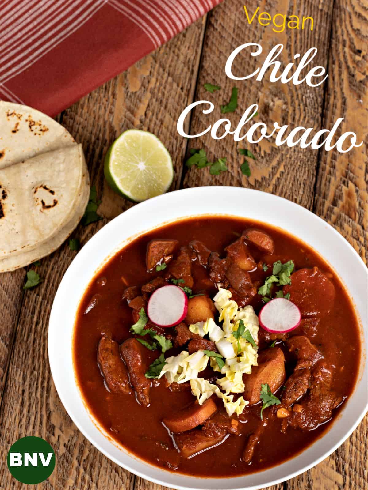 A big bowl of my vegan Chile Colorado garnished with cabbage, radishes, cilantro, and corn tortillas