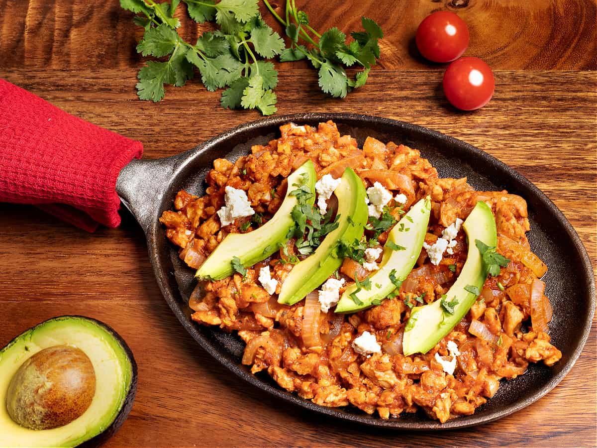 iron skillet platter of vegan tinga with avocado slices